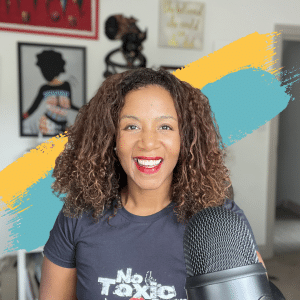 Picture of Alex Klein, founder of Wyrl Beauty. Alex is a black woman with coily brown hair. She is wearing a t-shirt and is sat behind a microphone. She is facing the camera with a smile.